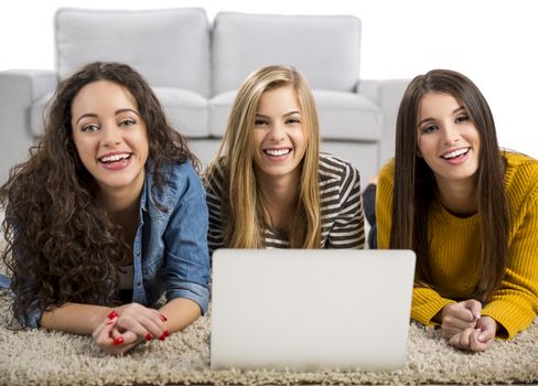 Happy teen girls studying at home with a laptop