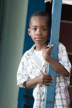 A child standing near an iron pillar and looking at the camera.