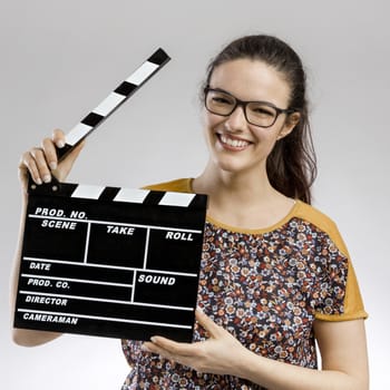 Portrait of a happy woman playing with a clapboard