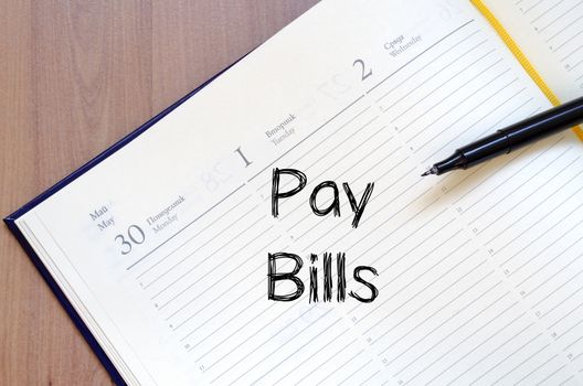 Pay bills text concept write on notebook with pen