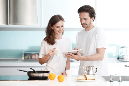 Happy couple cooking breakfast together in the kitchen