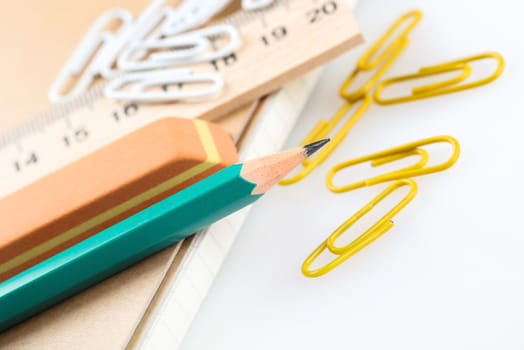 notebook, eraser, ruler, pencil and paperclips on white background