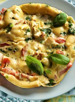 Fluffy Omelet with Vegetables, Greens and Basil Leafs on Grey Plate closeup