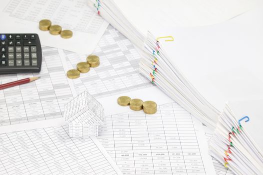 House on finance account have blur step pile of gold coins and pencil with calculator and pile overload paperwork of report and receipt with colorful paperclip as background.