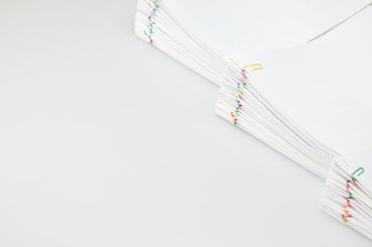 Pile overload document of report and receipt with colorful paperclip place on right with white background.