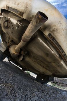 underside of a car with it's tail pipe as the primary focus point