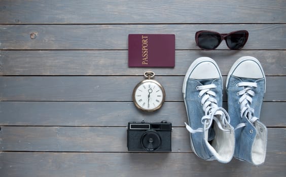 Travel items on a wooden background with passport, camera and shoes 