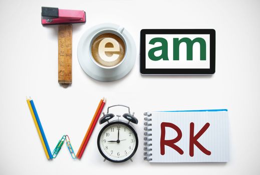 Team work spelt using stationery office tools including a digital tablet, clock and notepad