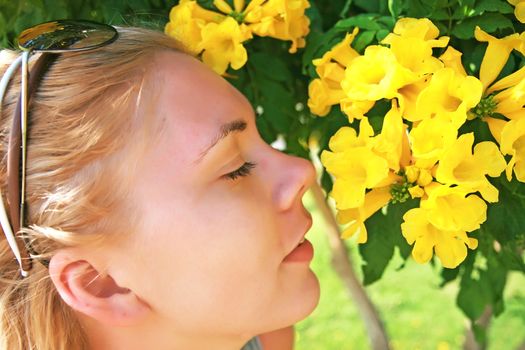 young woman smelling a yellow flower.