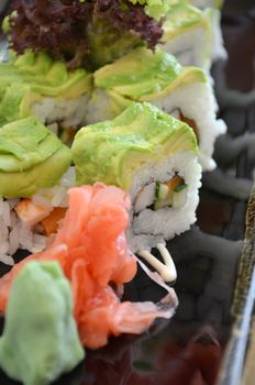 Veggie sushi roll on plate with avocado, kale and cucumber