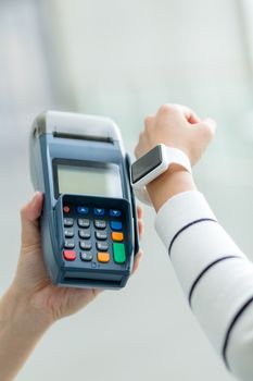 Woman using smart watch to settle the bill