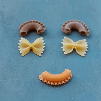 smiley face with raw pasta on blue background