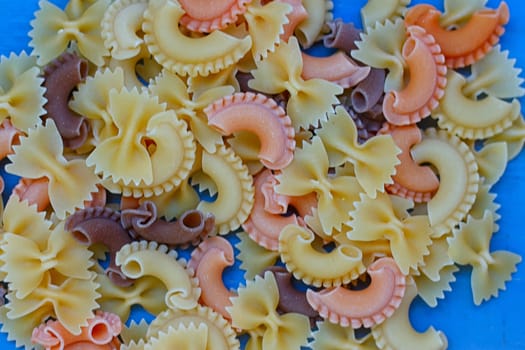 Multicolored different shapes of uncooked pasta in bulk on the table