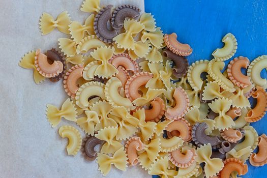 Multicolored different shapes of uncooked pasta in bulk on the table