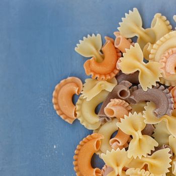 Multicolored different shapes of uncooked pasta in bulk on the table