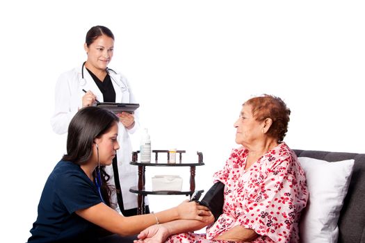 Nurse measuring blood pressure on Senior woman while doctor takes notes.