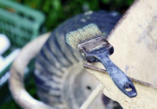 Old used paint brush put on the top of wheelbarrow. Paint brush after painting.