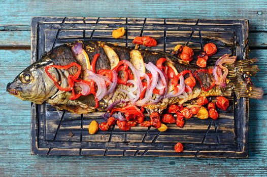 Baked fish in spices with vegetables on kitchen cutting board