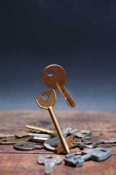 Door keys standing and flying above wooden board against dark background