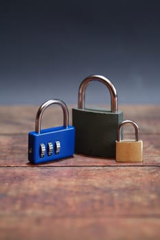 Three padlocks on wooden boaed against dark background