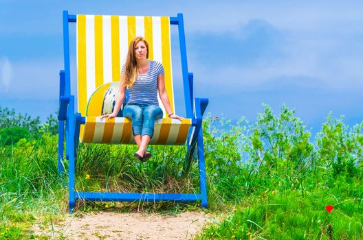 Gigantic deckchair with young women in front of a blue sky.

