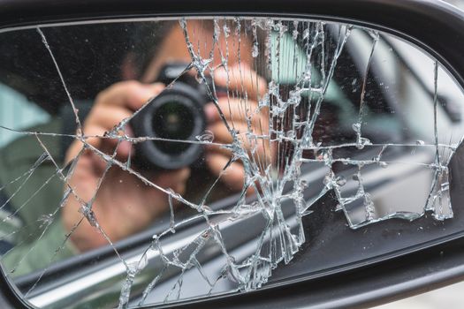 Mirror image of a photographer in the broken car mirror