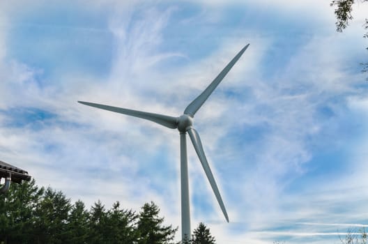 Wind turbine for electricity production photographed from below against a dramatic sky.