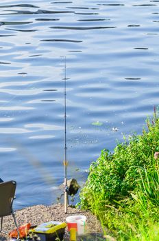 Individual fishing rod on a support with bait in the water.