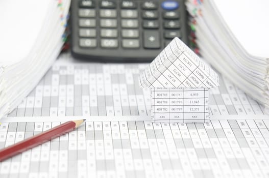 Brown pencil and house on finance account have blur calculator with pile of document as background.