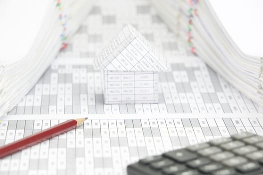 Brown pencil on finance account have blur calculator and blur house with pile of document as foreground and background.
