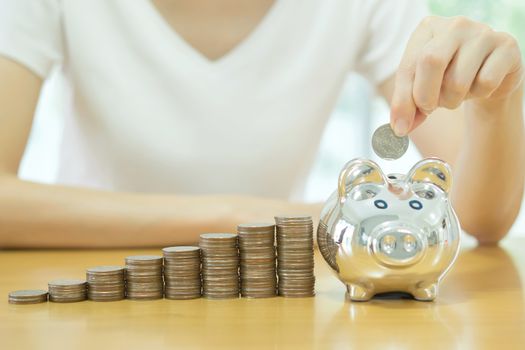 saving money-young woman putting a coin into a money-box-close up
