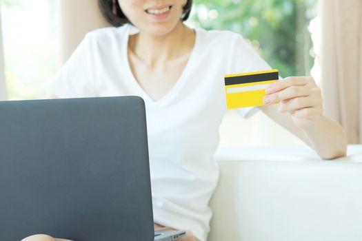 Concept for Internet shopping: woman with laptop and credit card sitting on sofa, at home