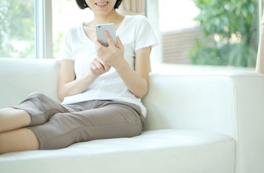 Young Woman Using Mobile Phone On Sofa At Home