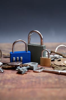 Three padlocks near keys on wooden board against dark background