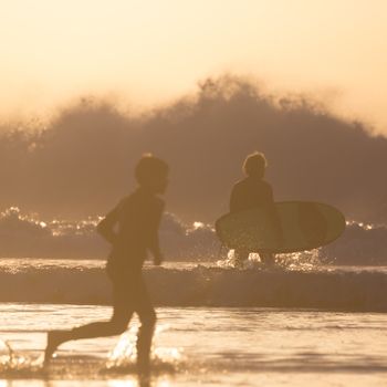 Silhouette of people on surfers beach in sunset.