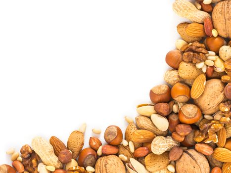 Background of mixed nuts - hazelnuts, almonds, walnuts, pistachios, peanuts, pine nuts peeled and not peeled - with copy space. Isolated one edge. Top view or flat lay