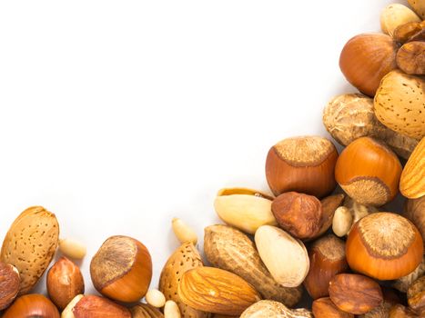 Background of closeup mixed nuts - hazelnuts, almonds, walnuts, pistachios, peanuts, pine nuts peeled and not peeled - with copy space. Isolated one edge. Top view or flat lay