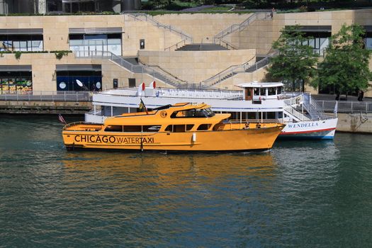 A yellow Water Taxi on the Chicago River docks near a Wendella sightseeing boat. With copy space.