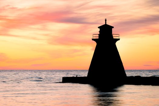 Lake Huron lighthouse silhouetted against a beautiful sunset.