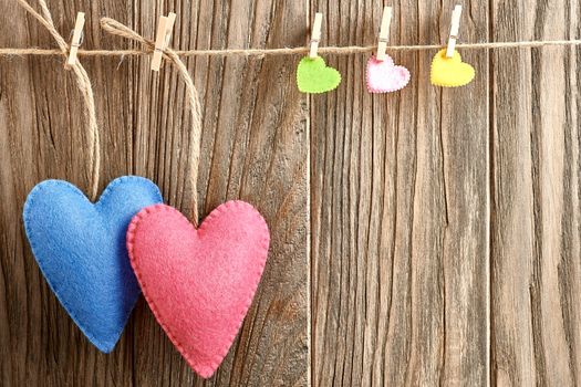 Love hearts, Valentines Day. Hearts couple, handmade, hanging on rope. Vintage romantic style on wooden background. Vivid unusual greeting card, multicolored felt, copyspace