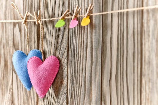 Love hearts, Valentines Day. Hearts couple, handmade, hanging on rope. Vintage romantic style on wooden background. Vivid unusual greeting card, multicolored felt, perspective, copyspace