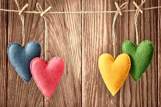 Love hearts, Valentines Day. Hearts couple, handmade, hanging on rope. Vintage retro romantic style on wooden background. Vivid unusual greeting card, multicolored felt, copyspace