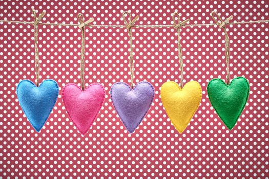 Love hearts, Valentines Day. Hearts set, handmade, hanging on rope. Vintage romantic style on red polka dots. Vivid retro unusual greeting card, multicolored felt, toned, copyspace