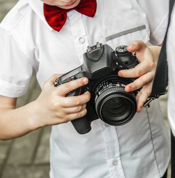 the child is holding the camera on the strap