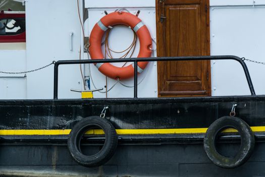Side view of an old steel ship with lifebuoy in harbor.