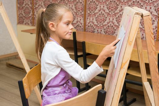 Girl artist with a smile look in the picture on the drawing lesson