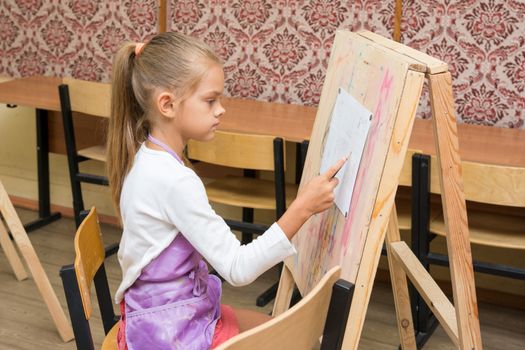 Girl artist paints on an easel to draw circle