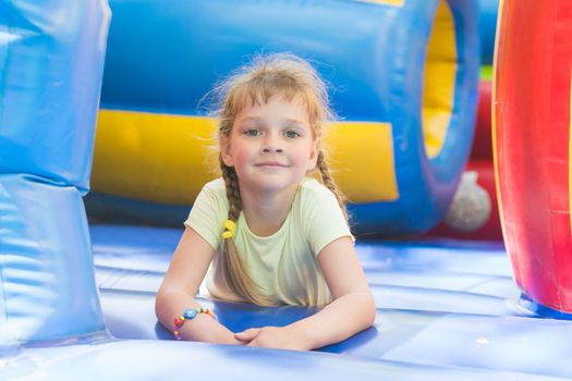 Disheveled five year old girl is playing on a big inflatable trampoline