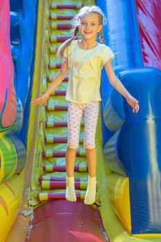 Happy girl jumping on an inflatable trampoline