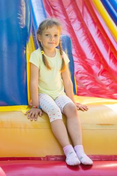 Five-year girl sitting on a big inflatable trampoline